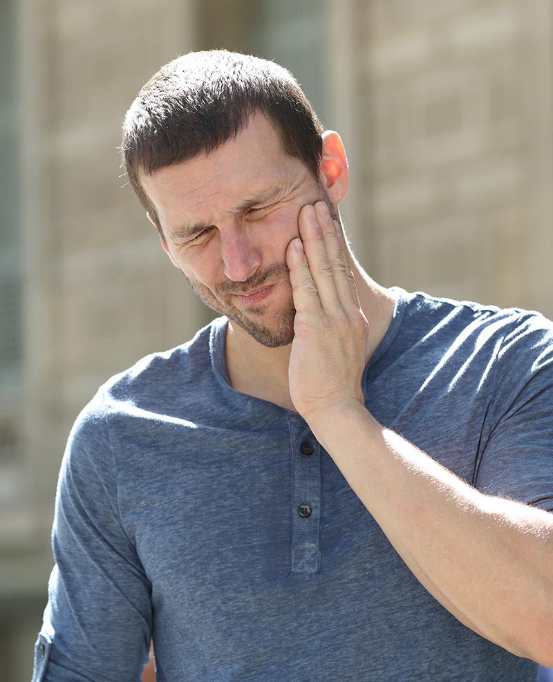 Stressed man suffering jaw pain in the street